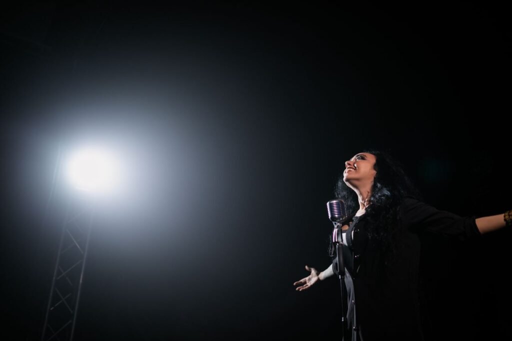 A passionate female singer performs on stage under a dramatic spotlight.